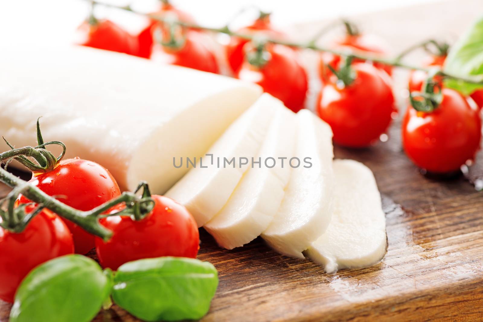 Ingredients for Caprese salad with mozzarella, tomato, basil and balsamic vinegar arranged on wooden table