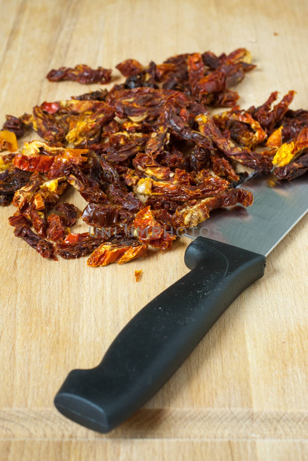 Sun dried tomatoes sliced up on a wooden cutting board.
