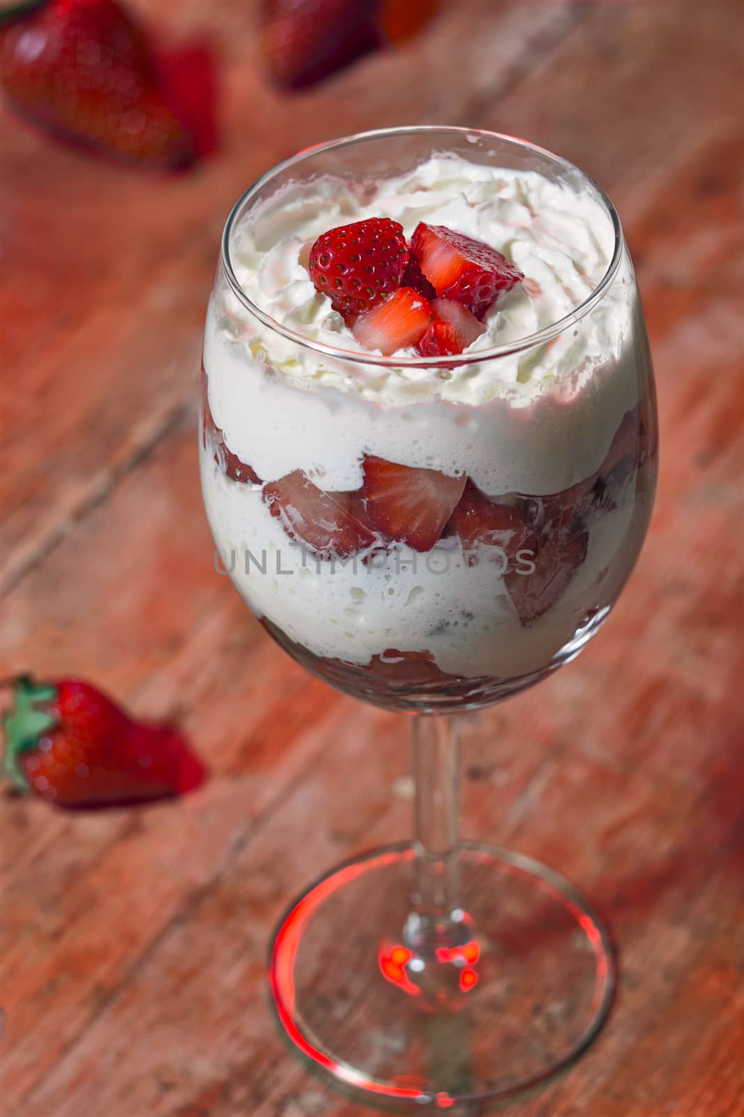 Glass with whipped cream and strawberries into small pieces