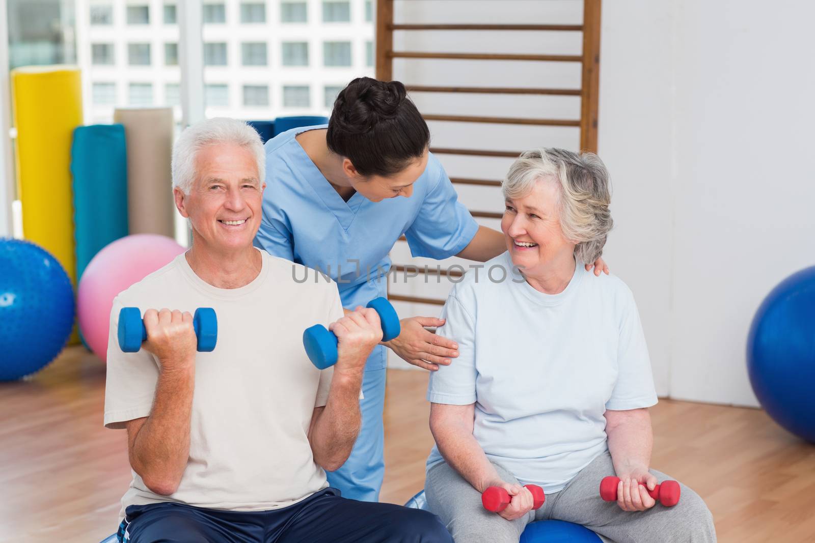 Happy female instructor with senior couple in gym