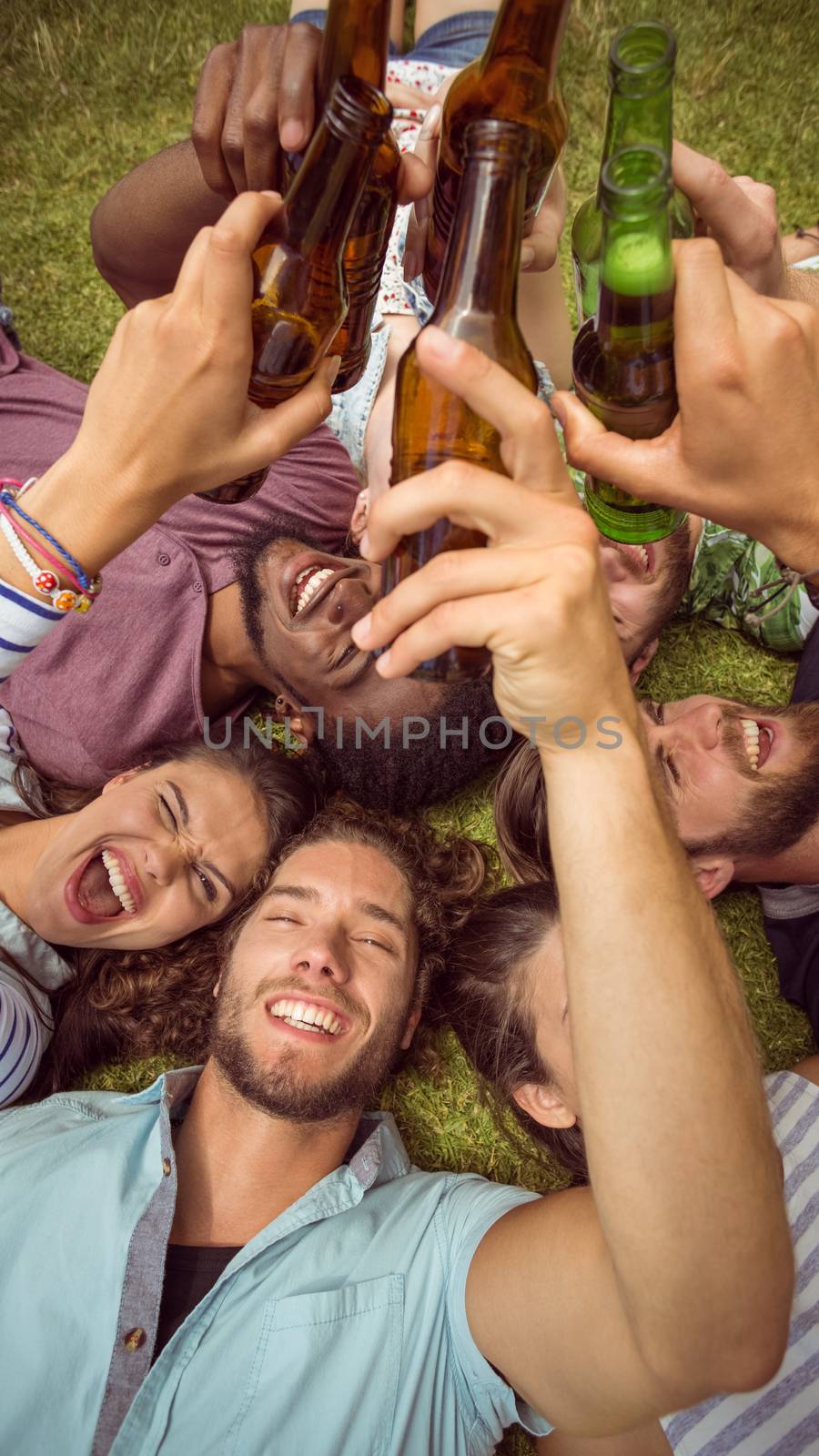 Happy young friends lying on grass on a summers day