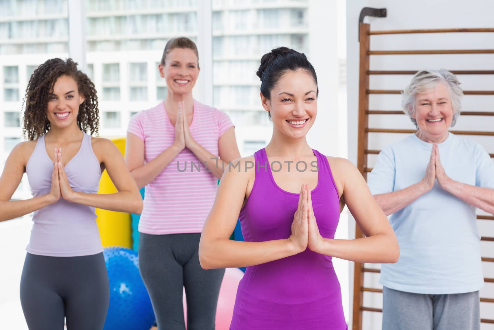 Happy female friends with hands clasped standing in gym