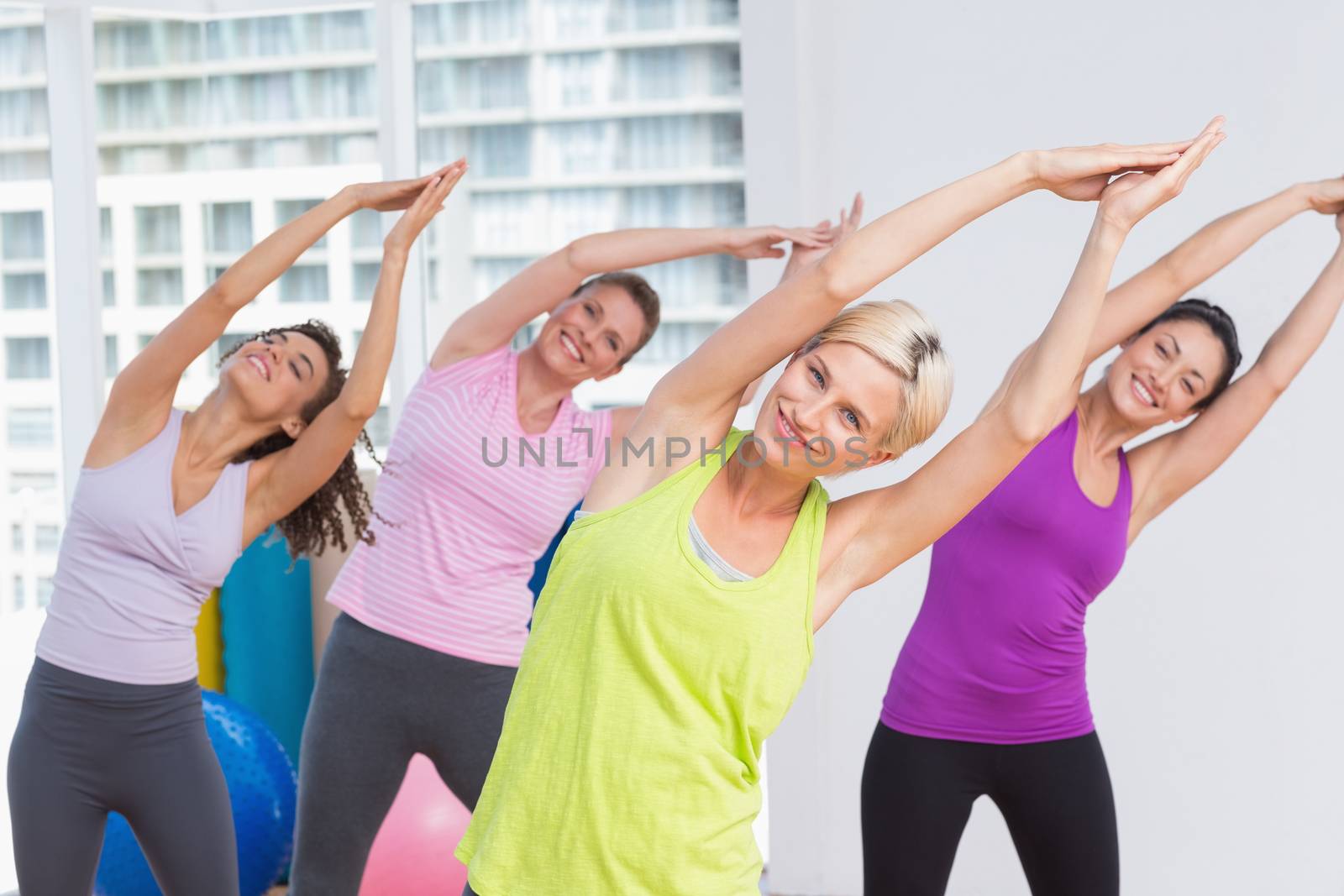 Portrait of happy women practicing stretching exercise at fitness studio
