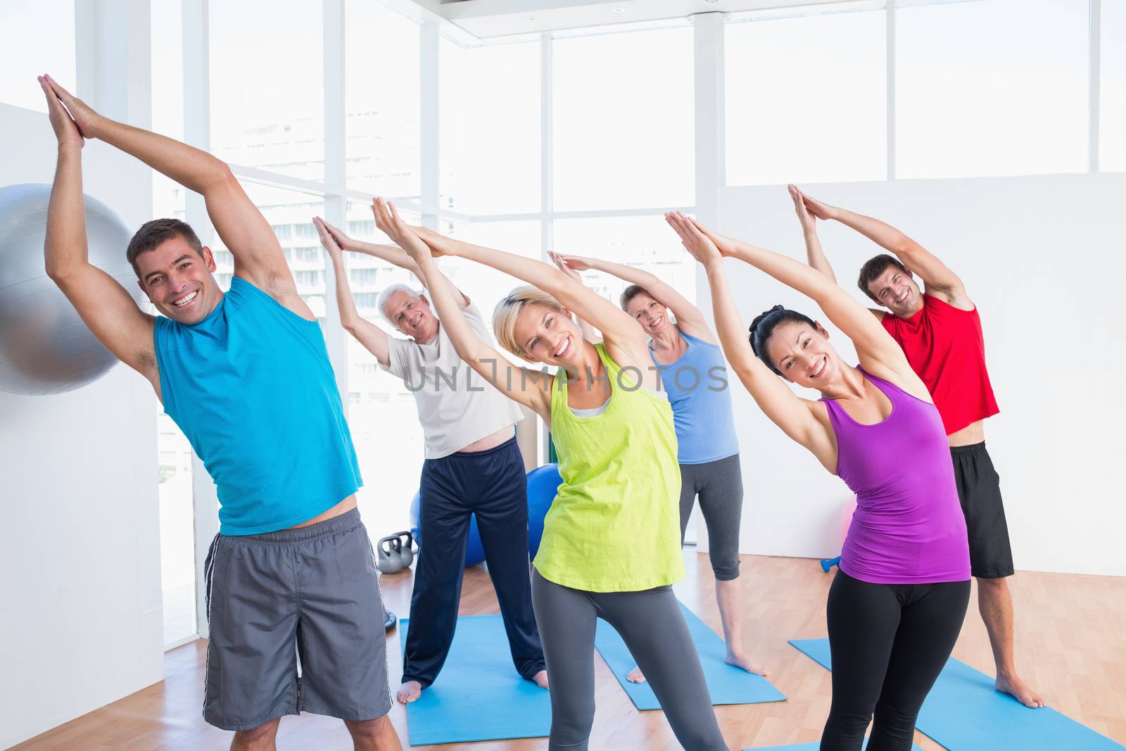 Portrait of happy people doing stretching exercise in yoga class