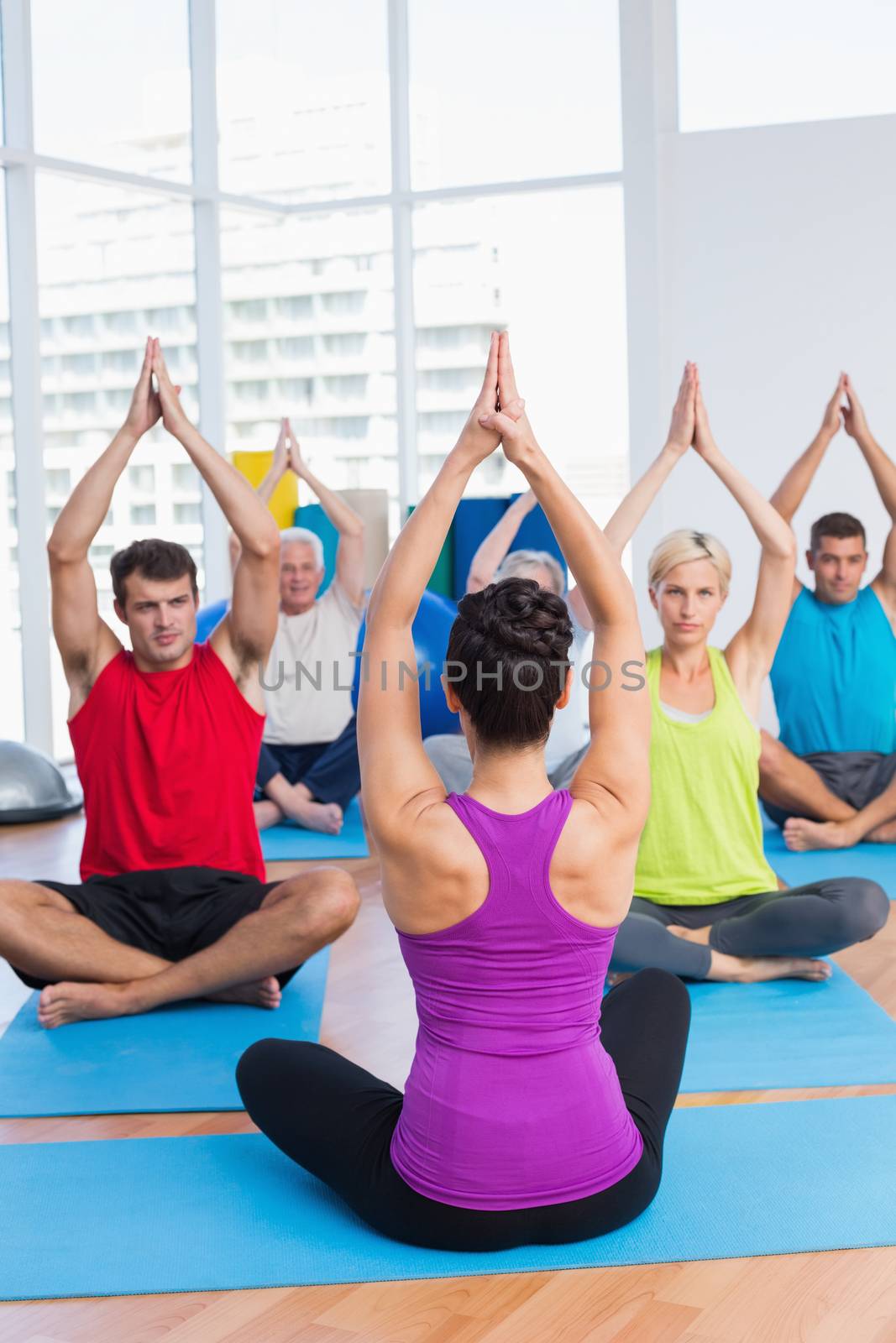 Female instructor with class practicing yoga in fitness club
