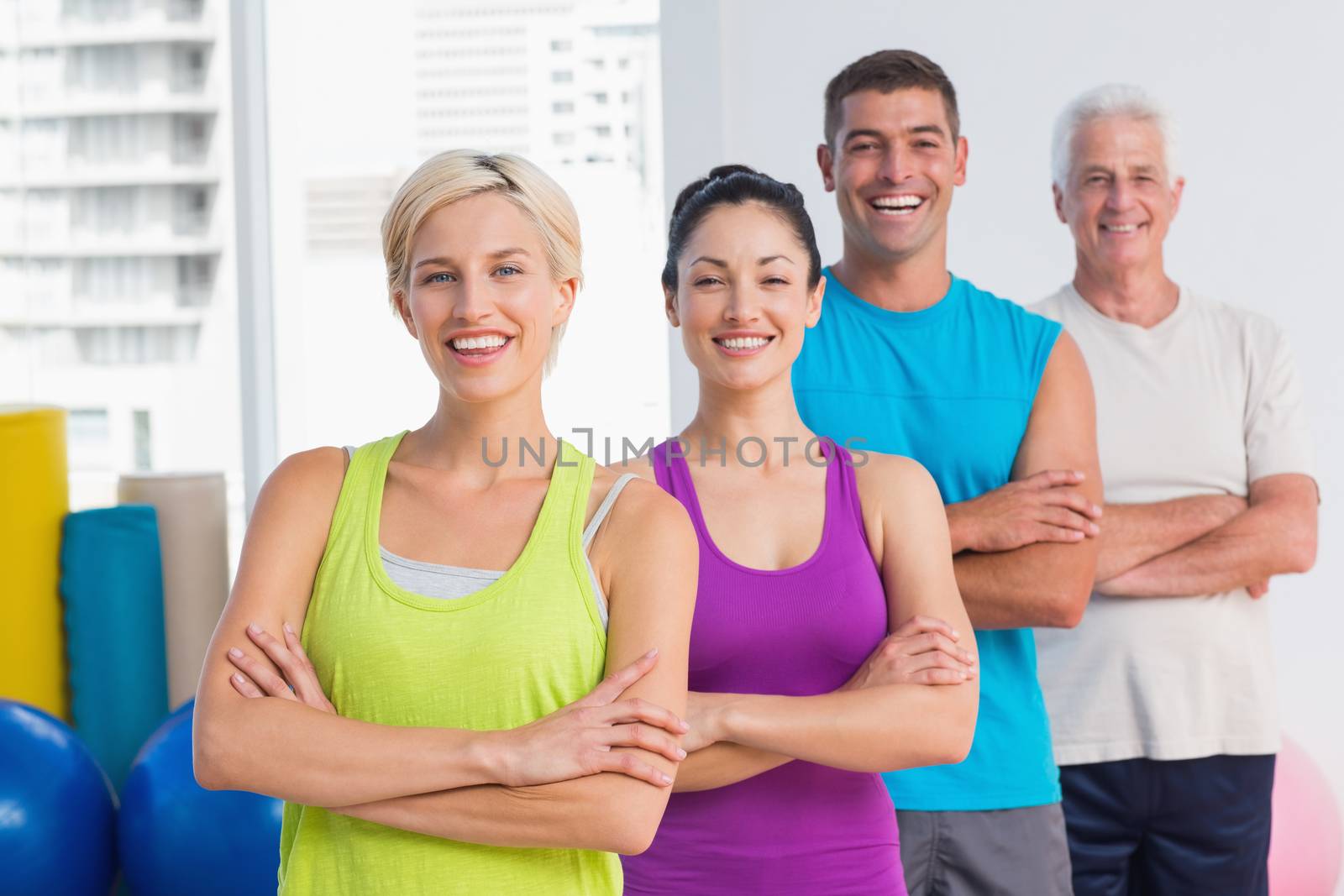 Portrait of confident fit people standing arms crossed at gym