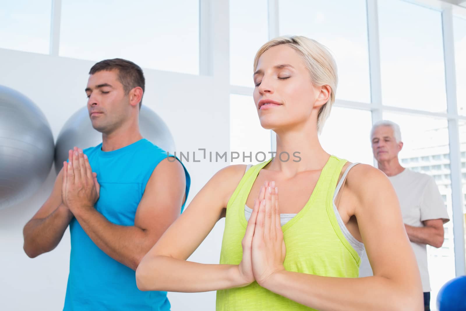 Fit people meditating with hands joined in gym class