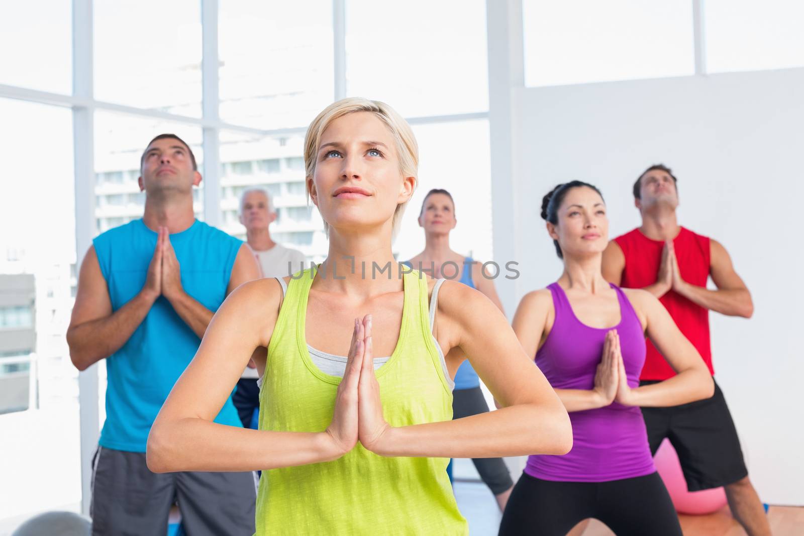 Female instructor with class meditating in fitness club