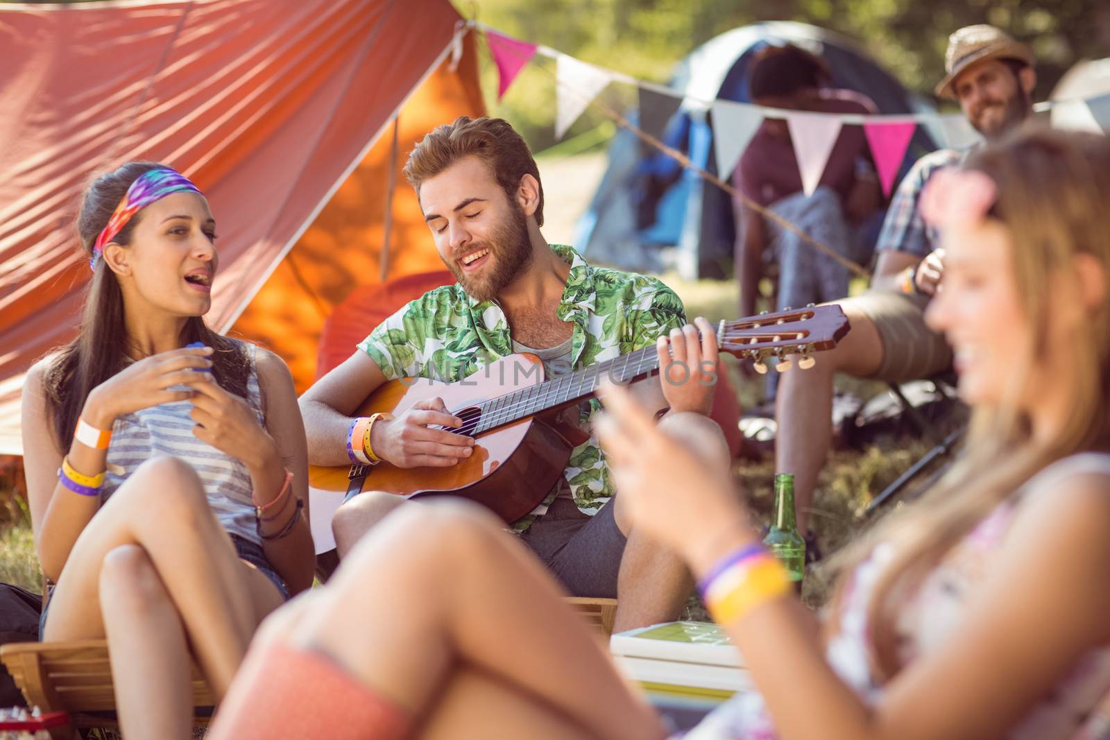 Handsome hipster playing the guitar at a music festival 