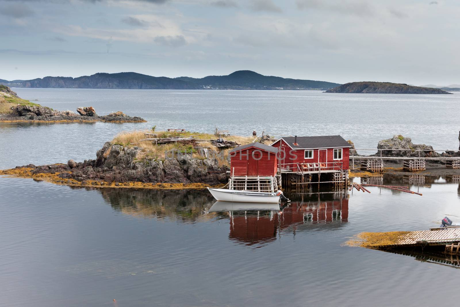 Red painted wooden fishing shacks at New Foundland, NL, Canada, Atlantic Ocean coast calm cove