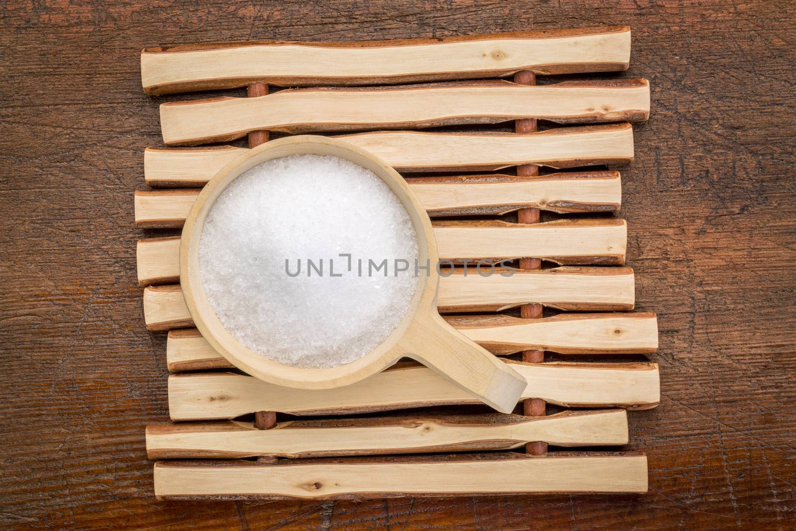 Epsom salts (Magnesium sulfate) in a rustic wooden scoop - relaxing bath concept