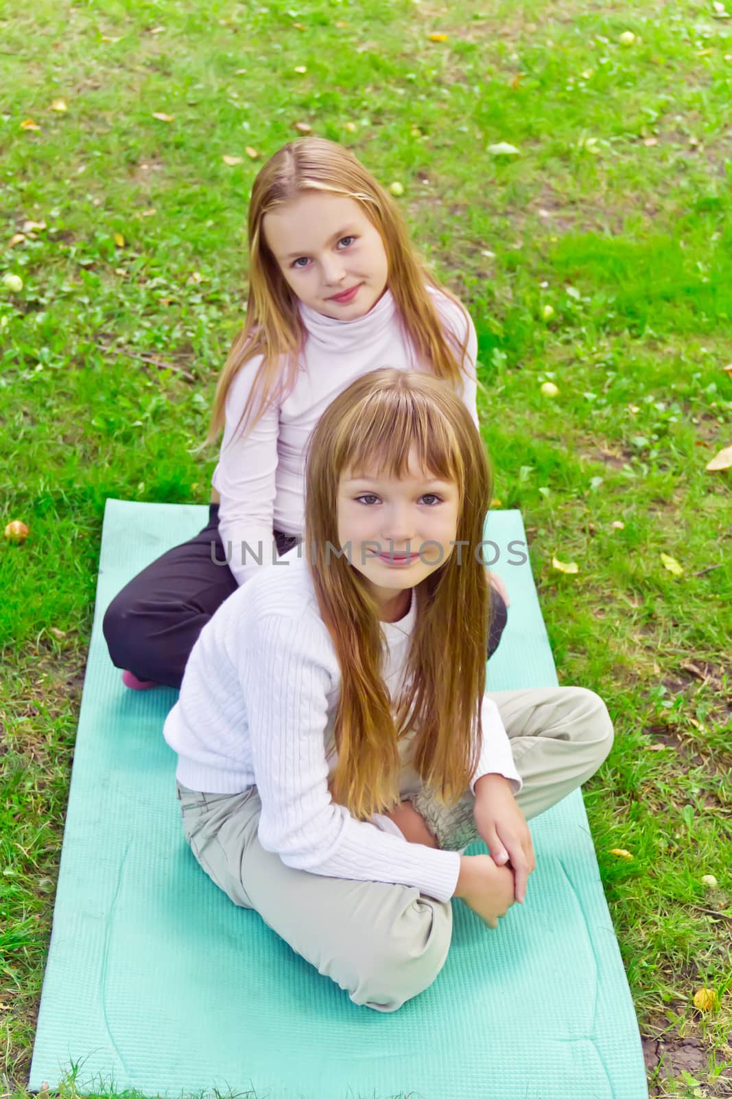 Photo of two girls sitting on grass in summer