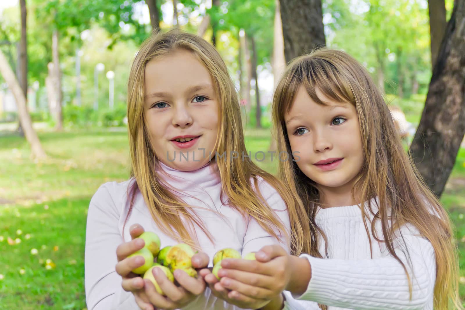 Photo of two girls with apples in summer