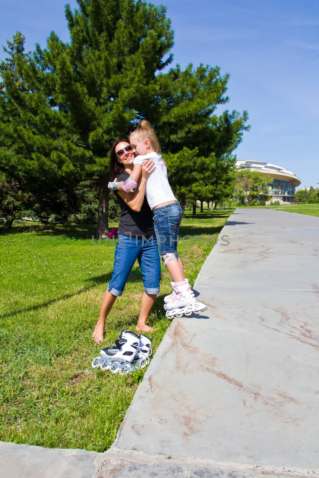 Learning mother and daughter on roller skates in summer