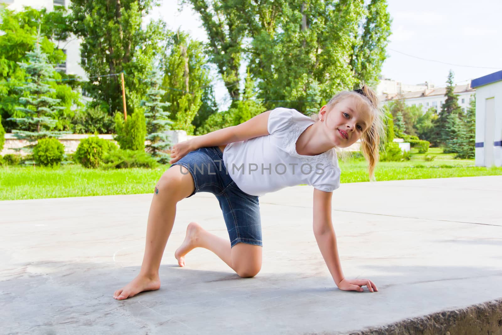 Cute girl draws chalk on asphalt in summer