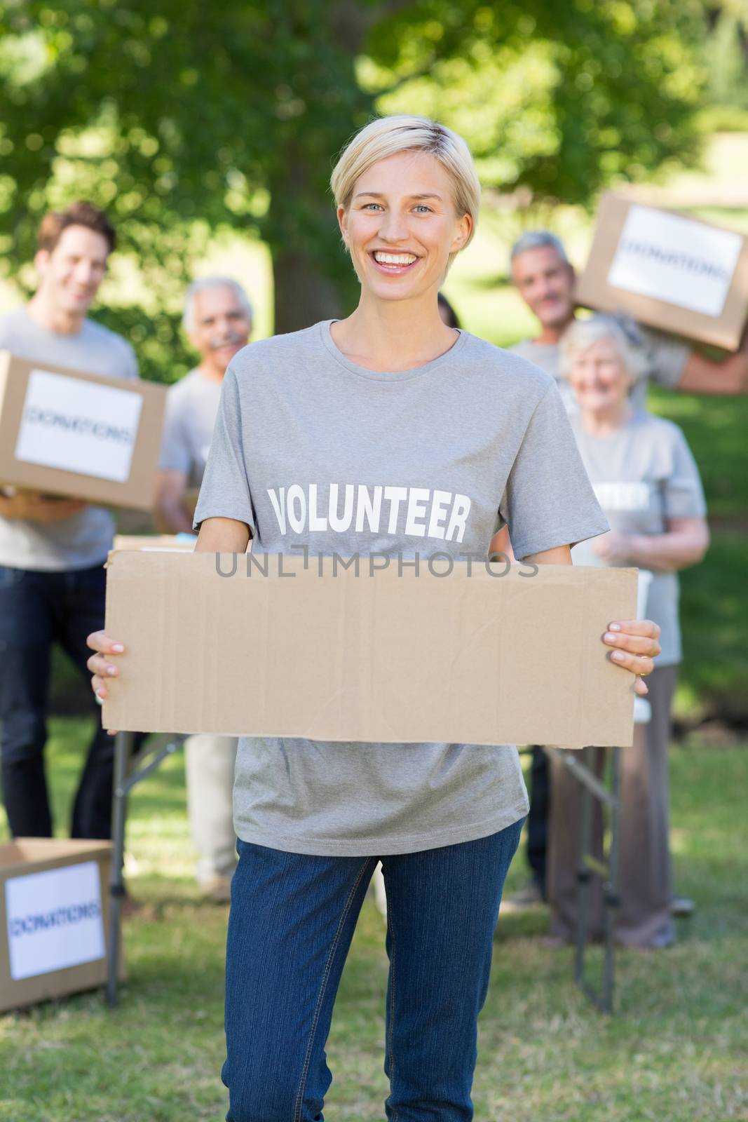 Happy volunteer blonde holding blank on a sunny day