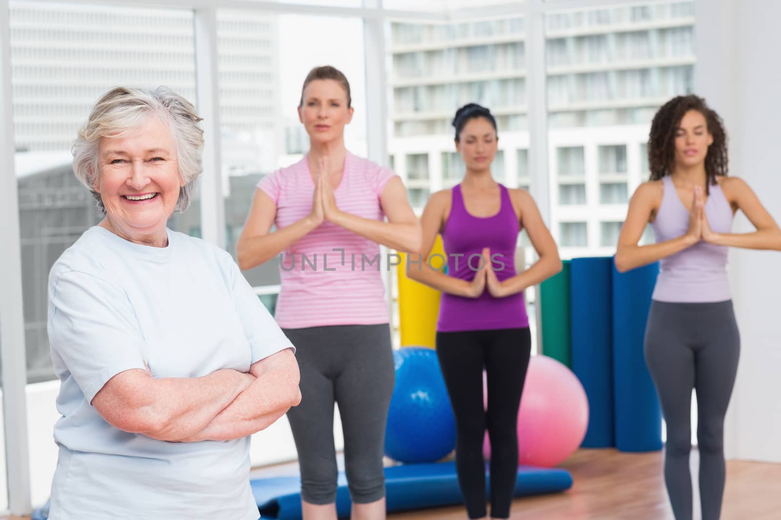 Senior woman with arms crossed standing in gym by Wavebreakmedia