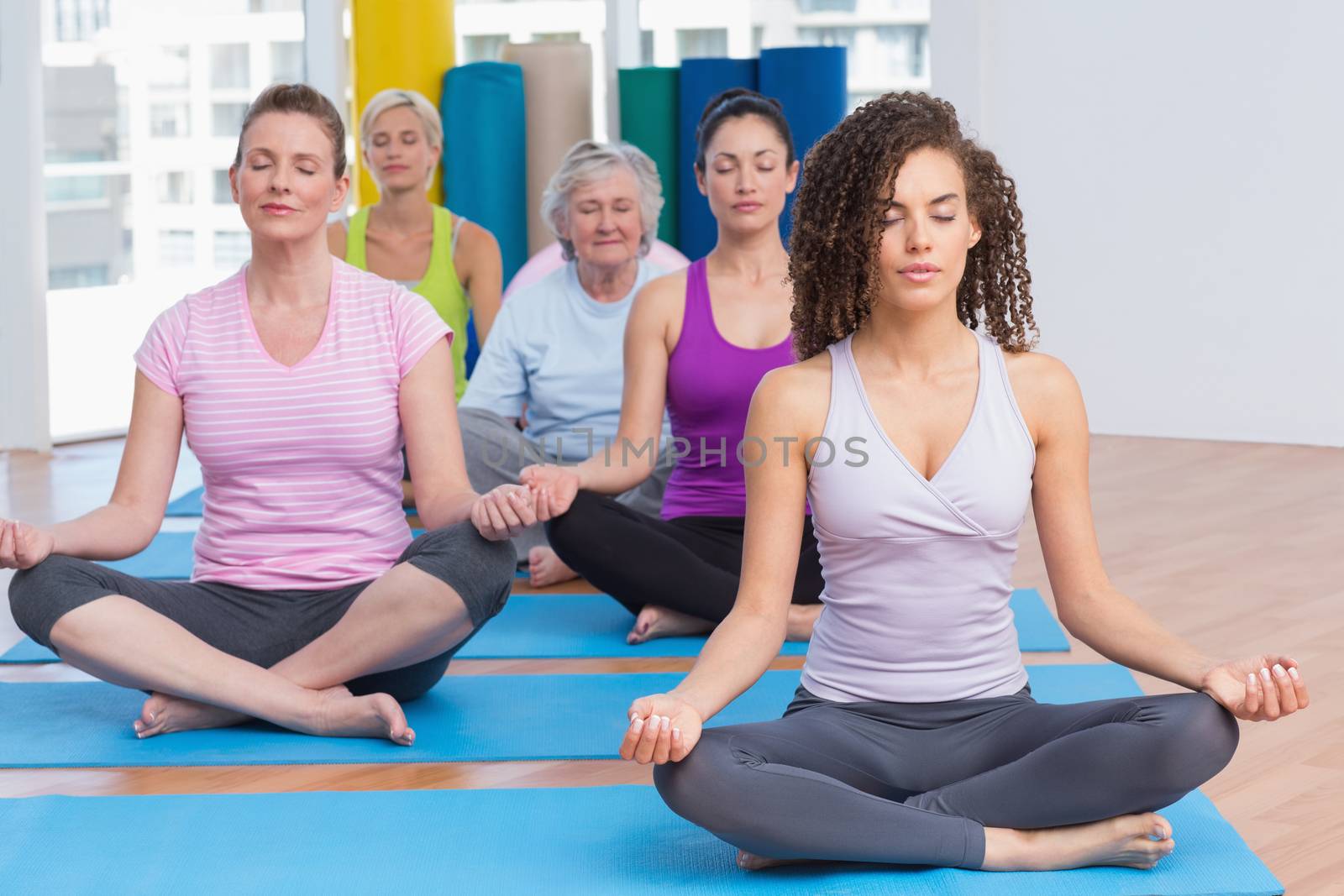 Fit women practicing lotus position in gym class