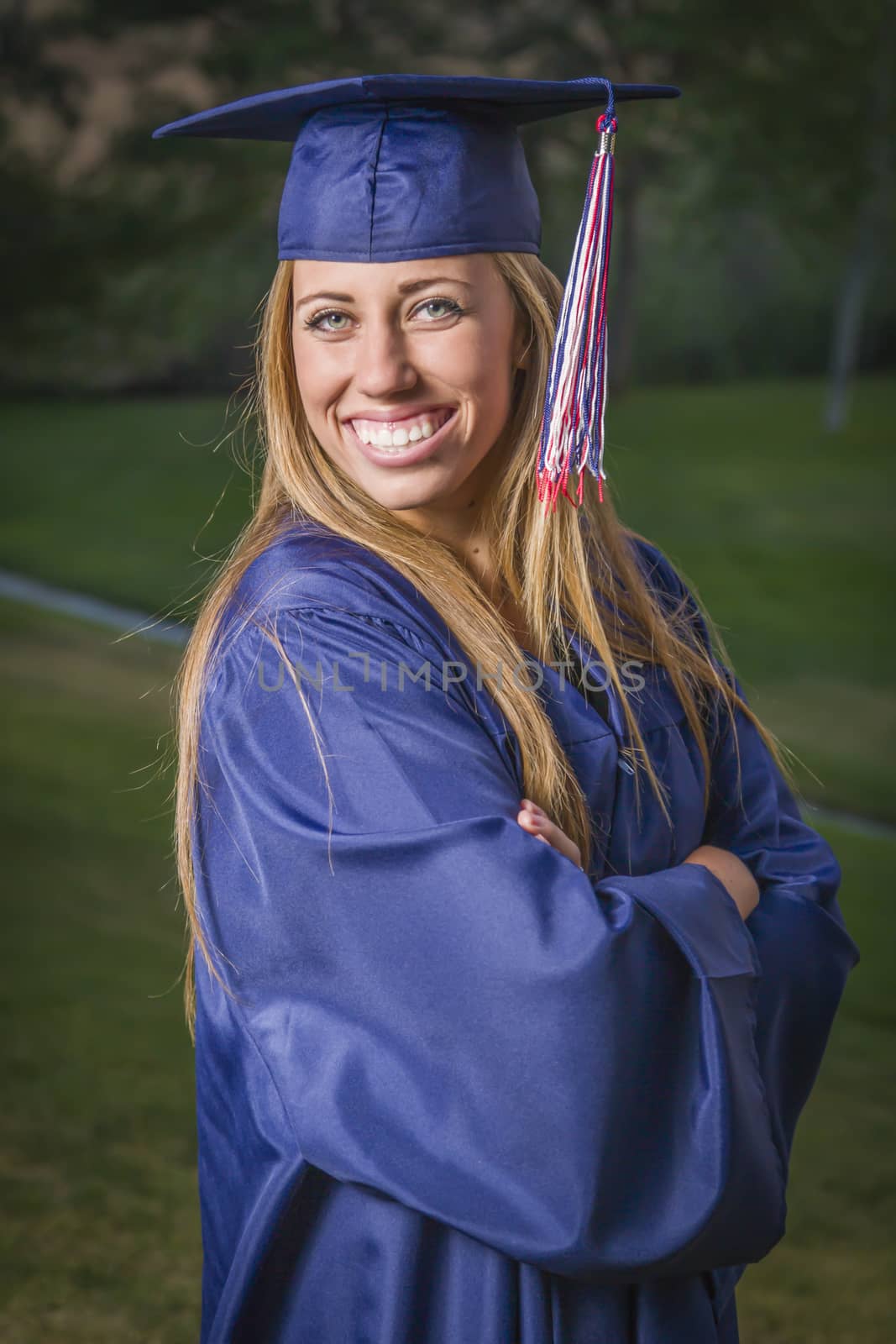 Smiling Young Woman Wearing Cap and Gown Outdoors.