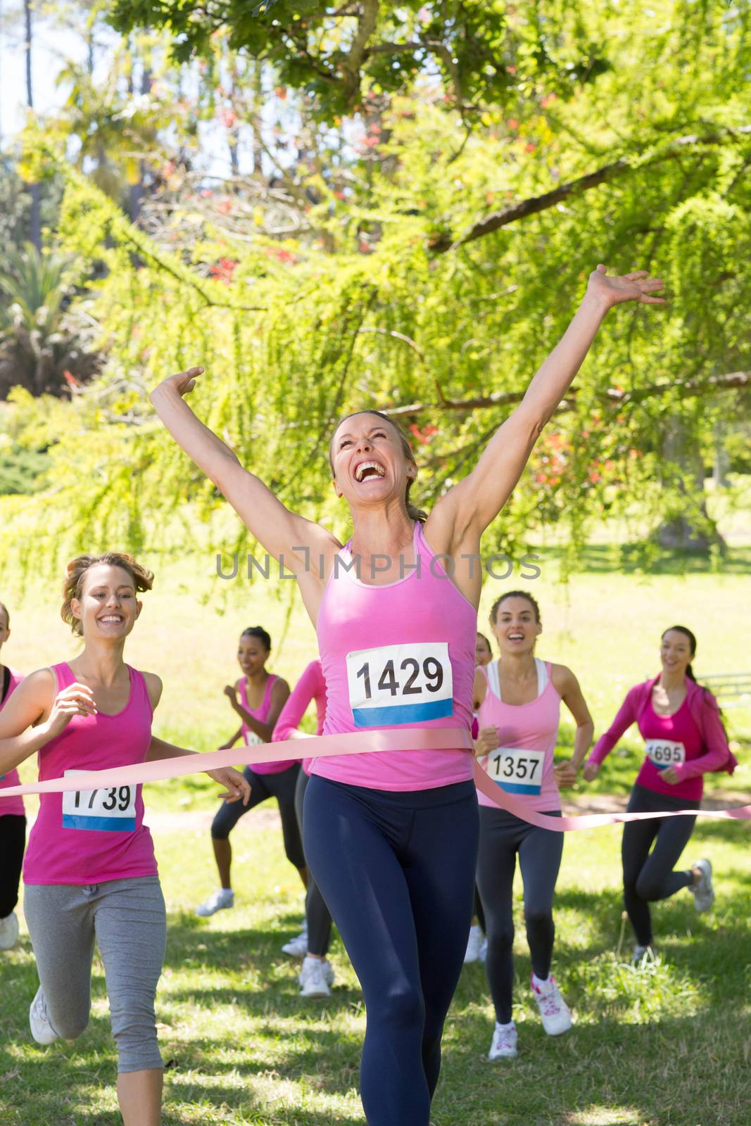 Smiling women running for breast cancer awareness on a sunny day