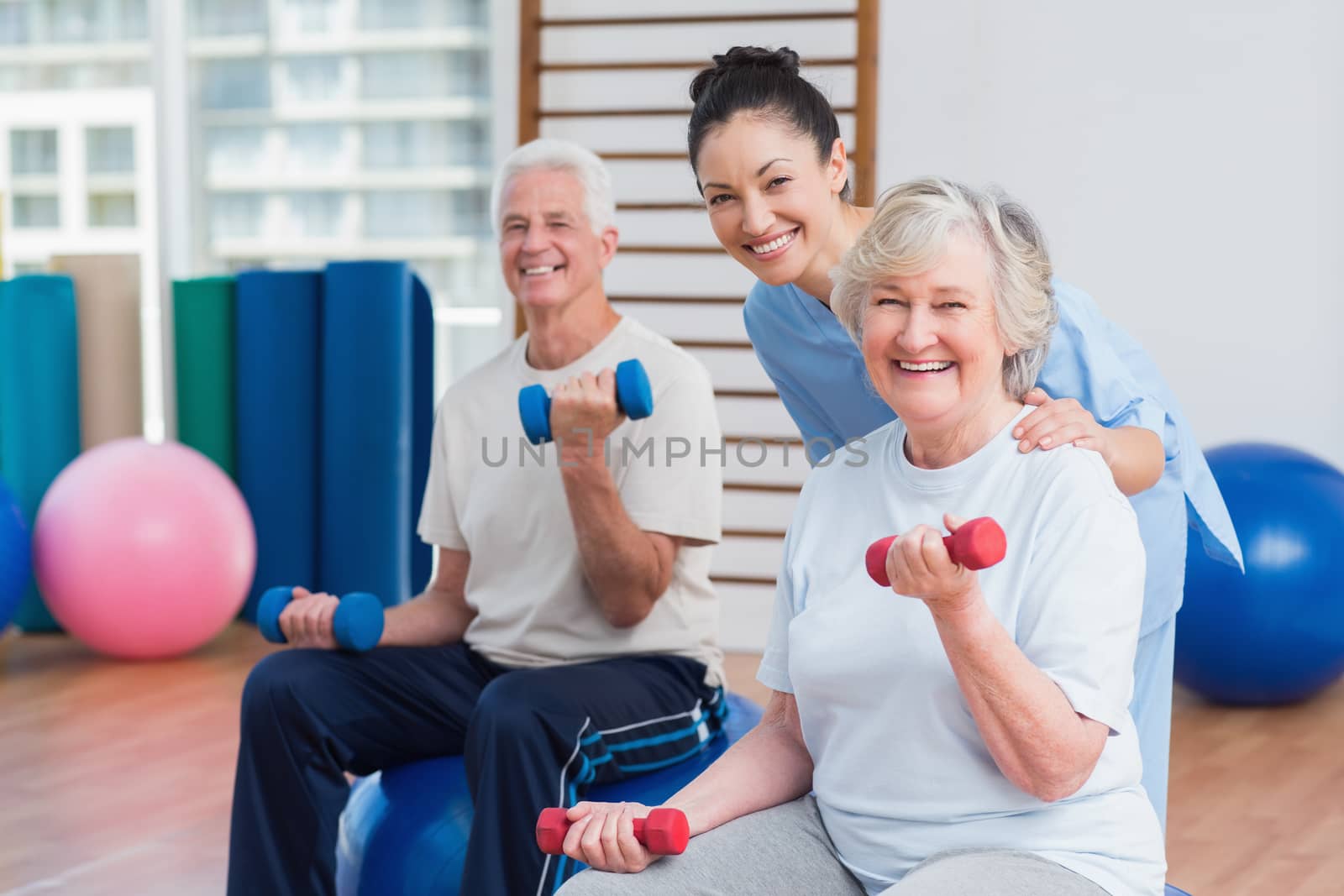 Portrait of happy female instructor with senior couple in gym