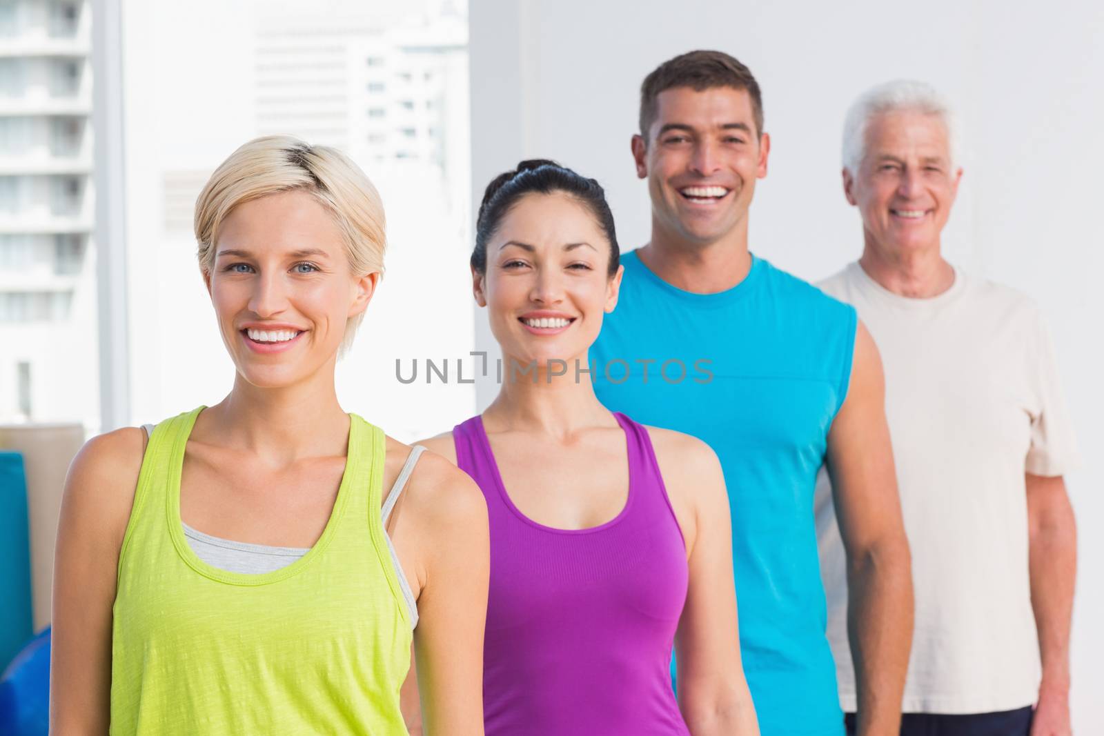 Portrait of cheerful women and men in sports wear at gym