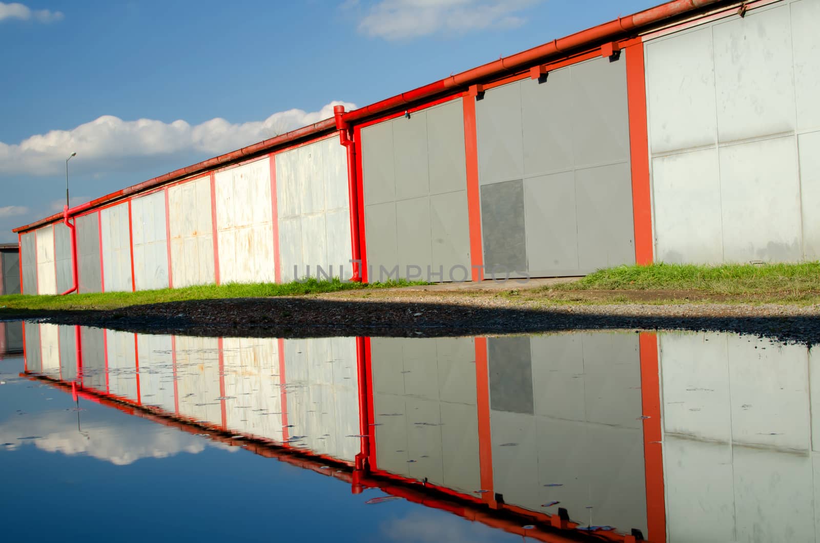 A lot of garages, puddle with reflection.