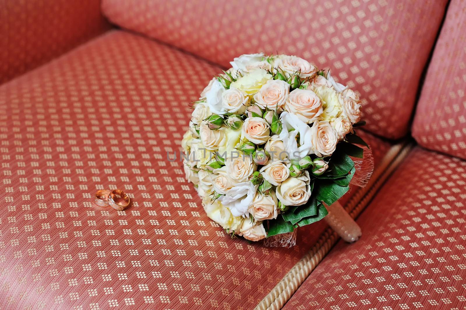 Pair of wedding rings and wedding bouquet on sofa by timonko