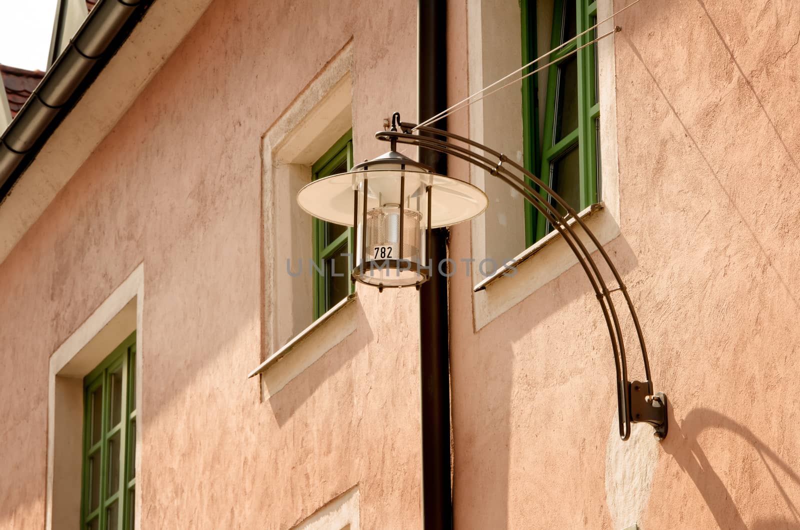 Street lamp on the pink house with green windows.