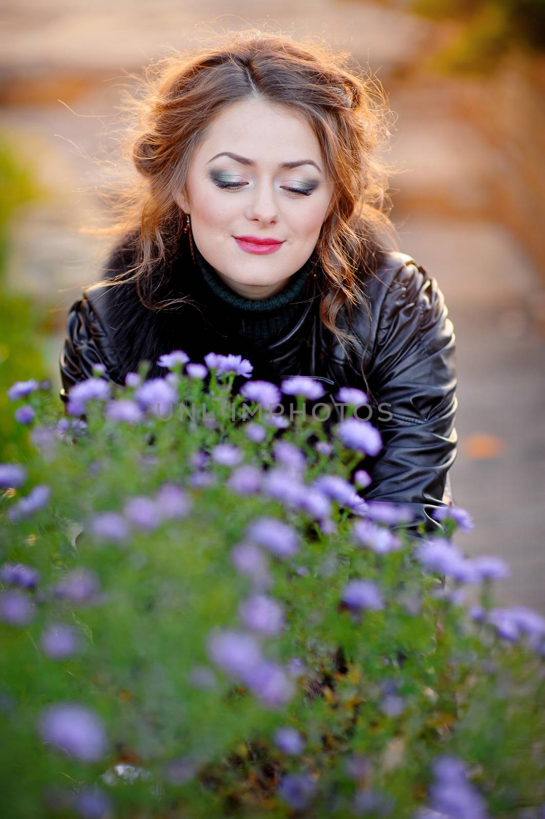Portrait of a young beautiful woman smiling outdoors looking at flowers