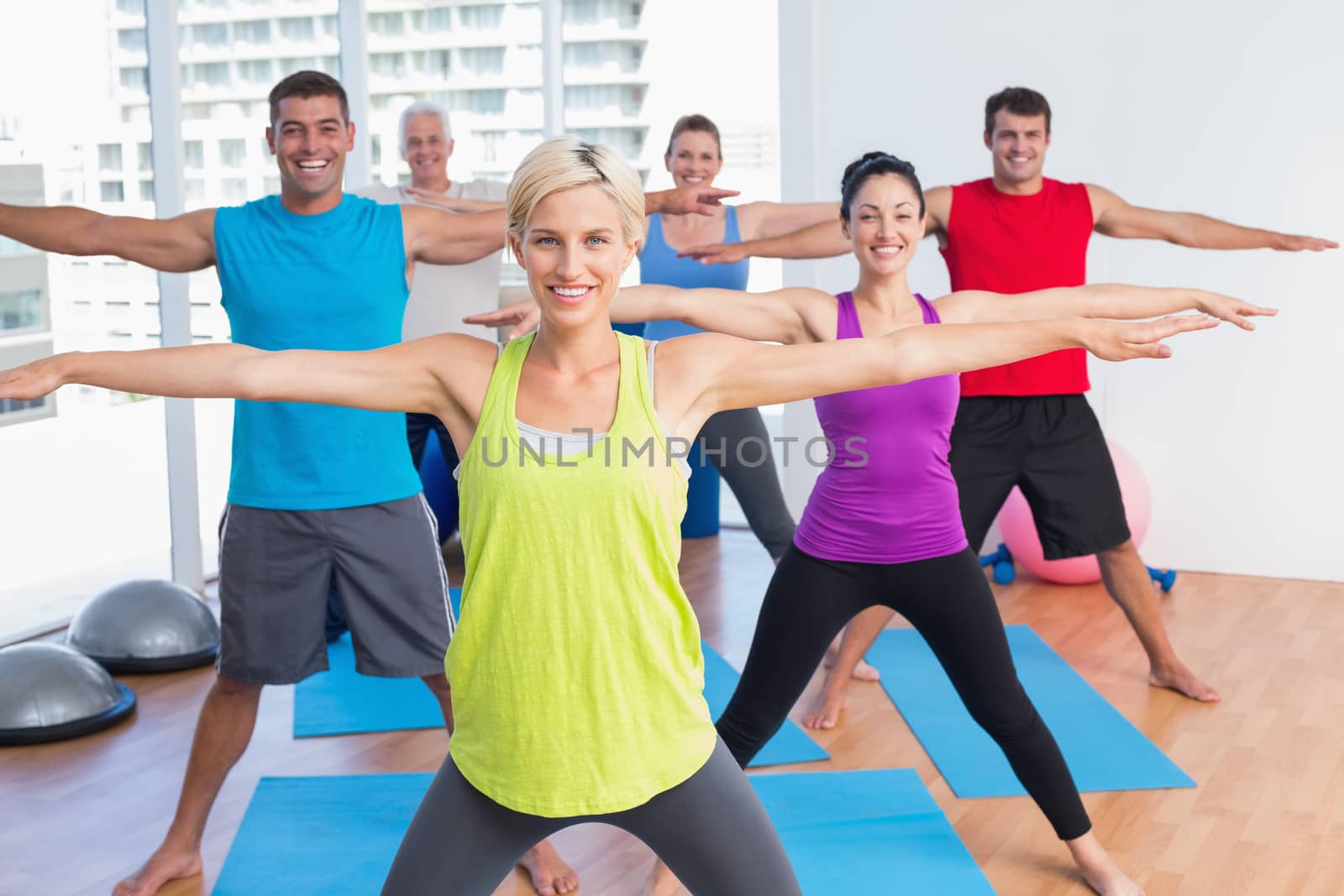 Portrait of happy female instructor with class exercising in fitness club