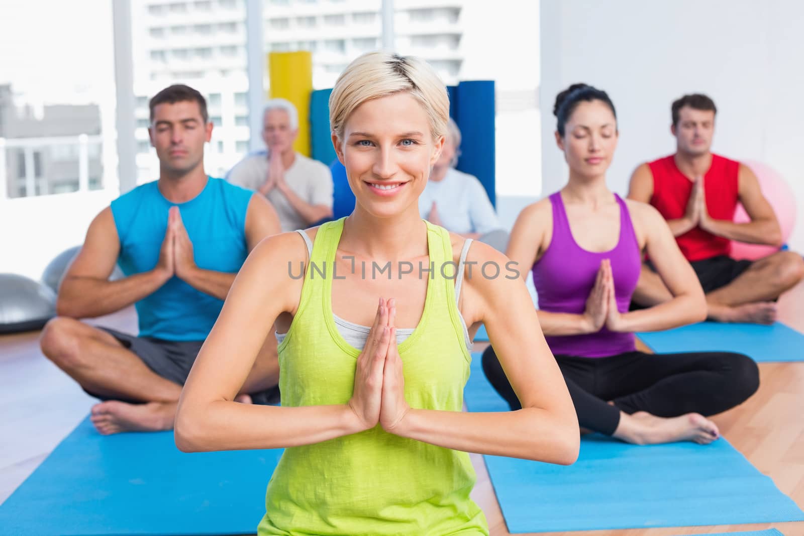 Portrait of happy woman with class meditating in fitness studio