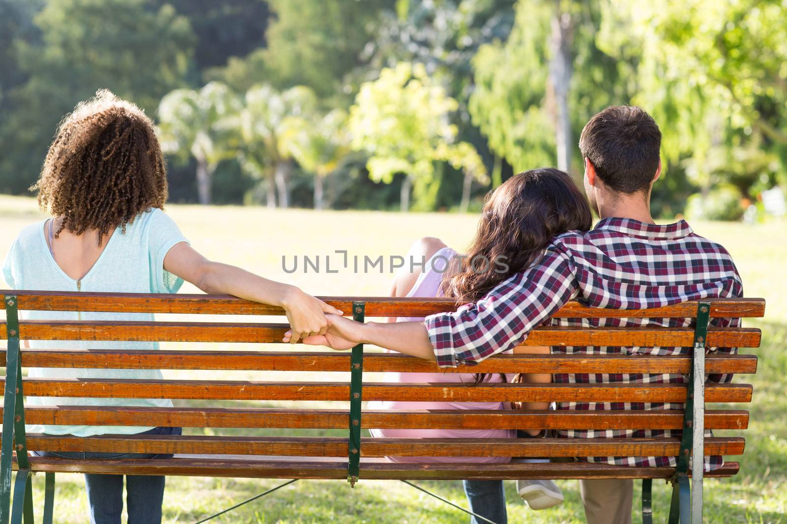 Lonely woman sitting with couple in park on a sunny day