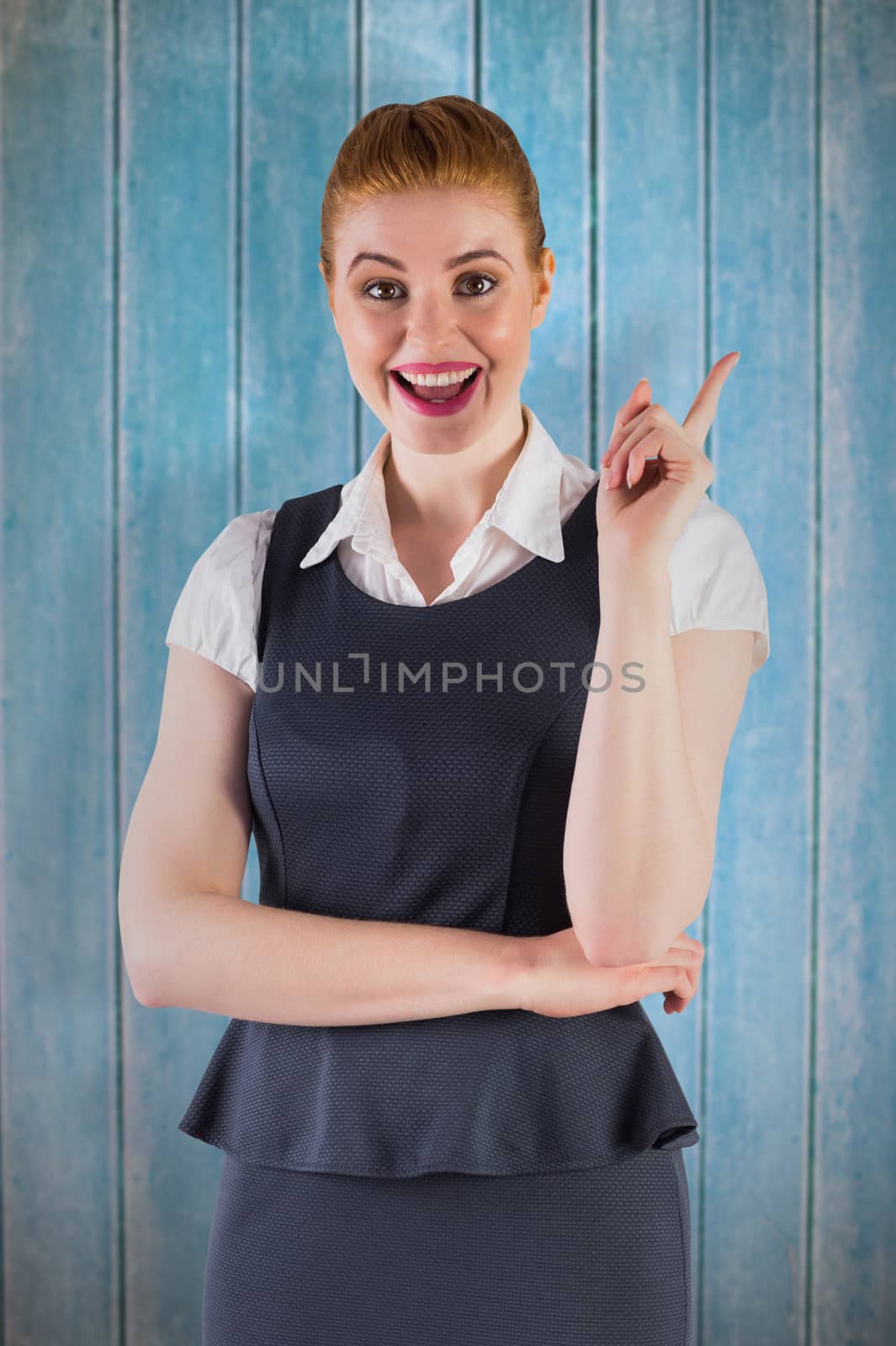 Redhead businesswoman pointing and smiling against wooden planks