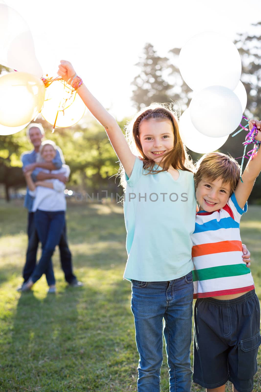Happy siblings holding balloons at the park  by Wavebreakmedia