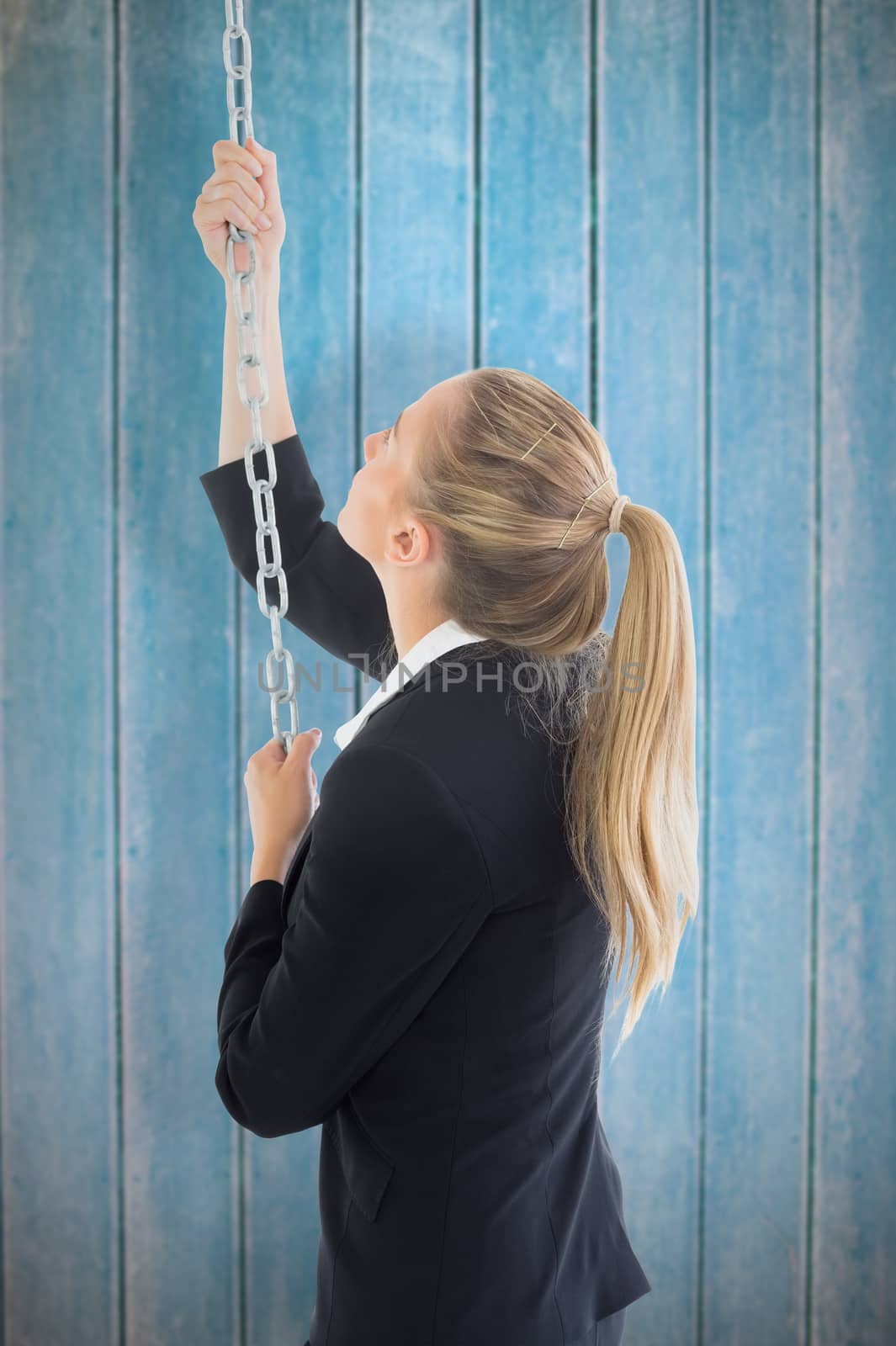 Businesswoman pulling a chain against wooden planks