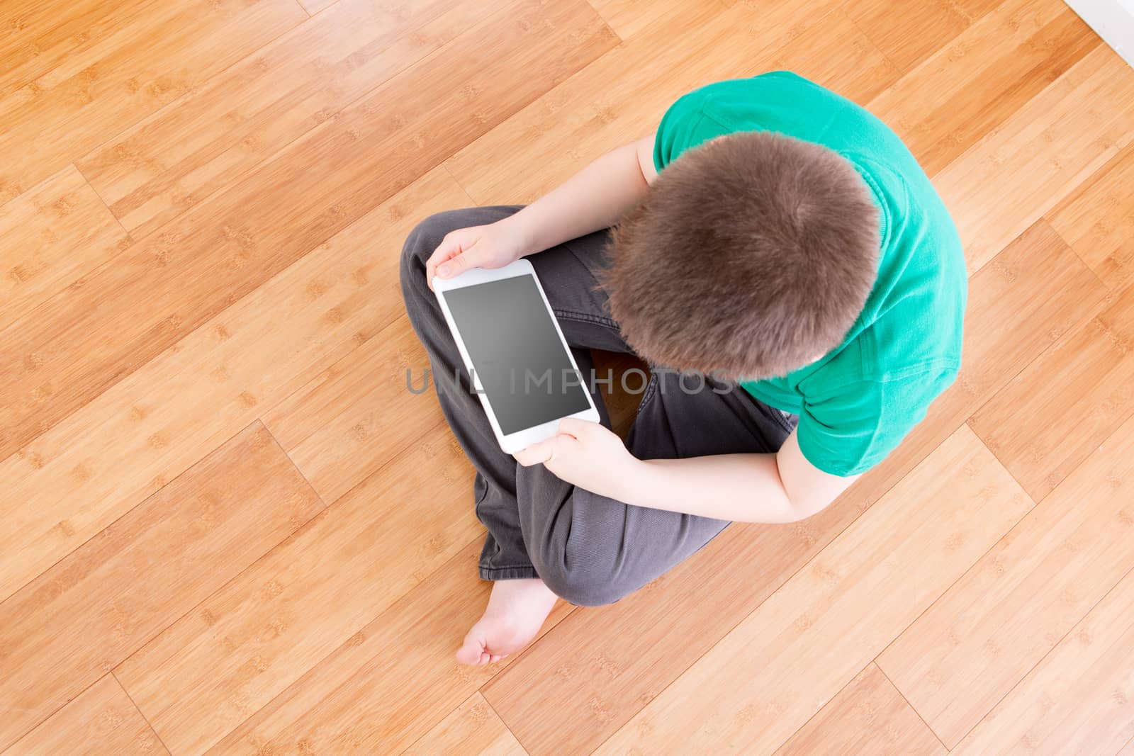 Boy on the Floor Holding Tablet in High Angle View by coskun