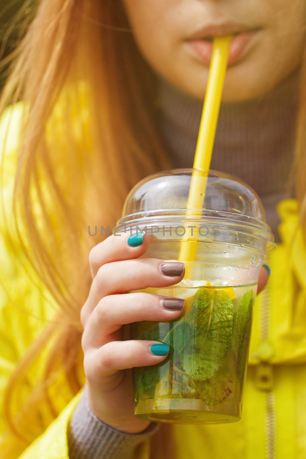 girl is drinking a large glass of lemonade. Close portrait