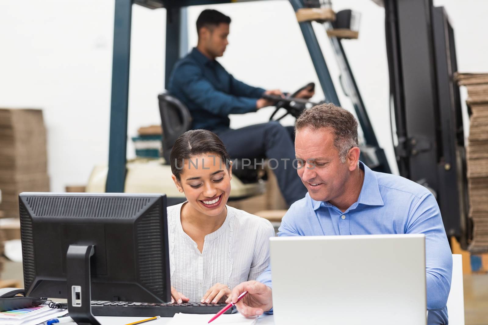 Warehouse managers working with laptop at desk by Wavebreakmedia