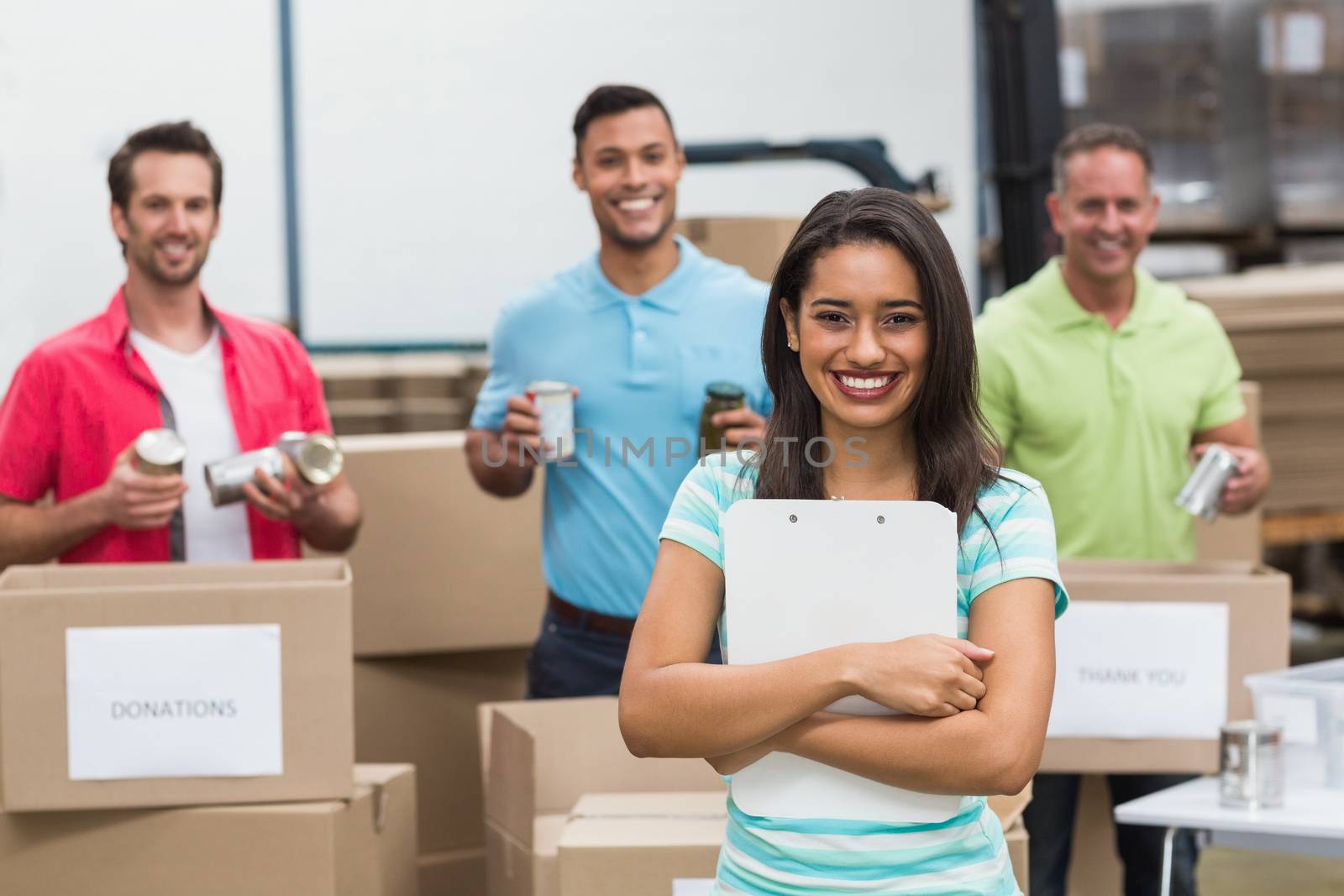 Smiling young female volunteer holding clipboard in a large warehouse