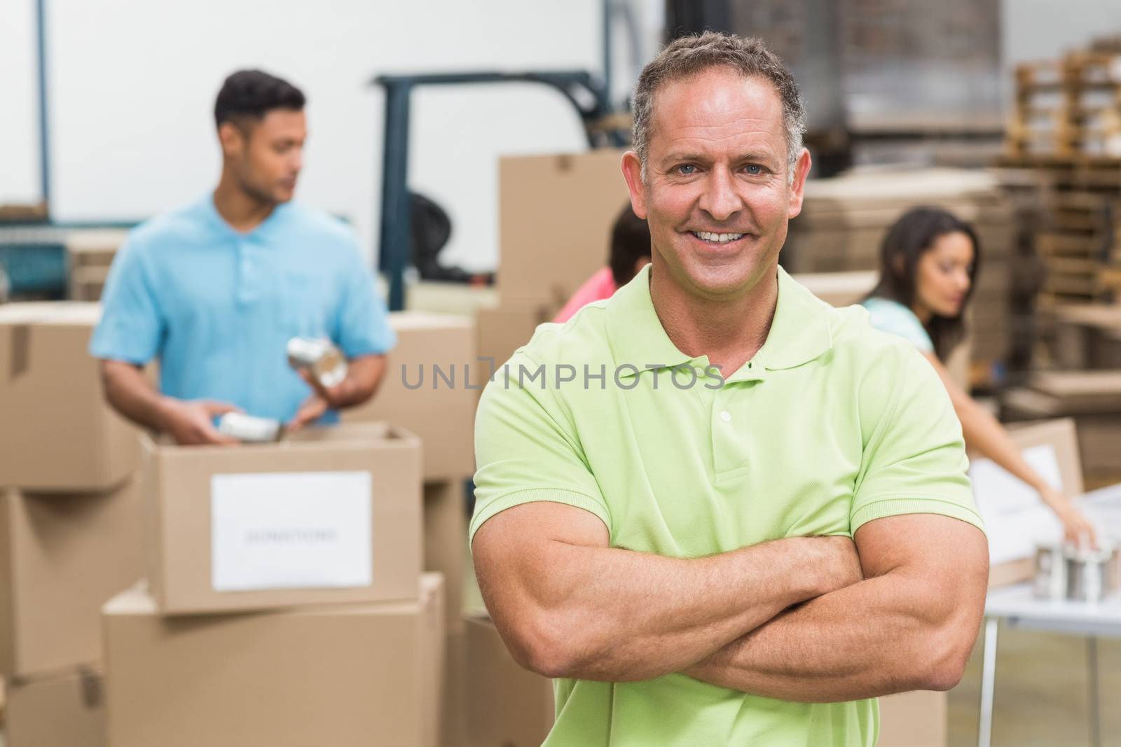 Portrait of a smiling volunteer with arms crossed in a large warehouse