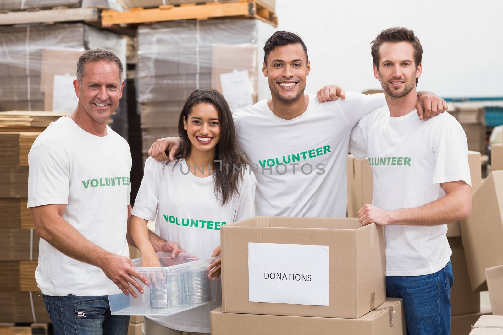 Team of volunteers smiling at camera in a large warehouse