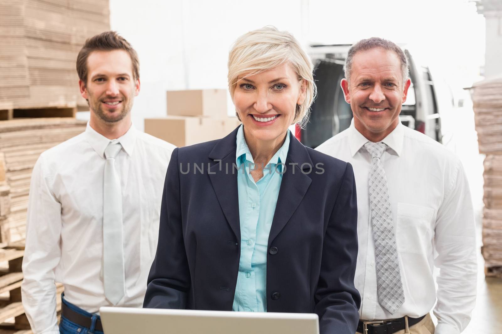 Warehouse team working together on laptop in a large warehouse