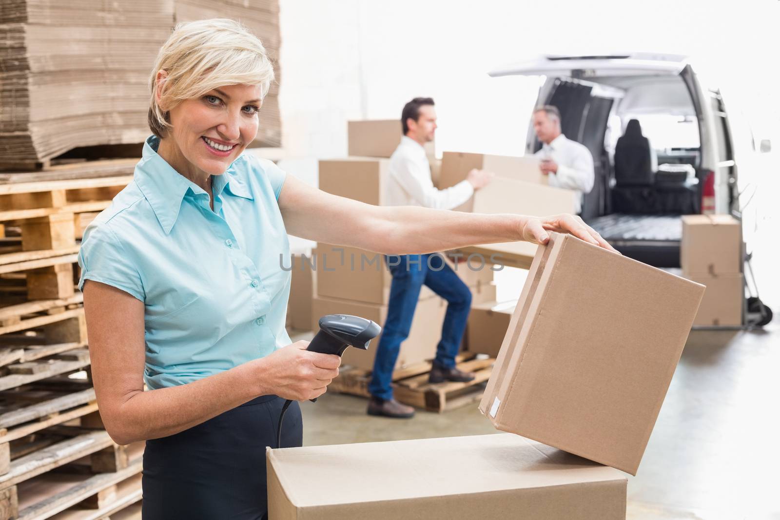 Smiling warehouse manager scanning package in warehouse