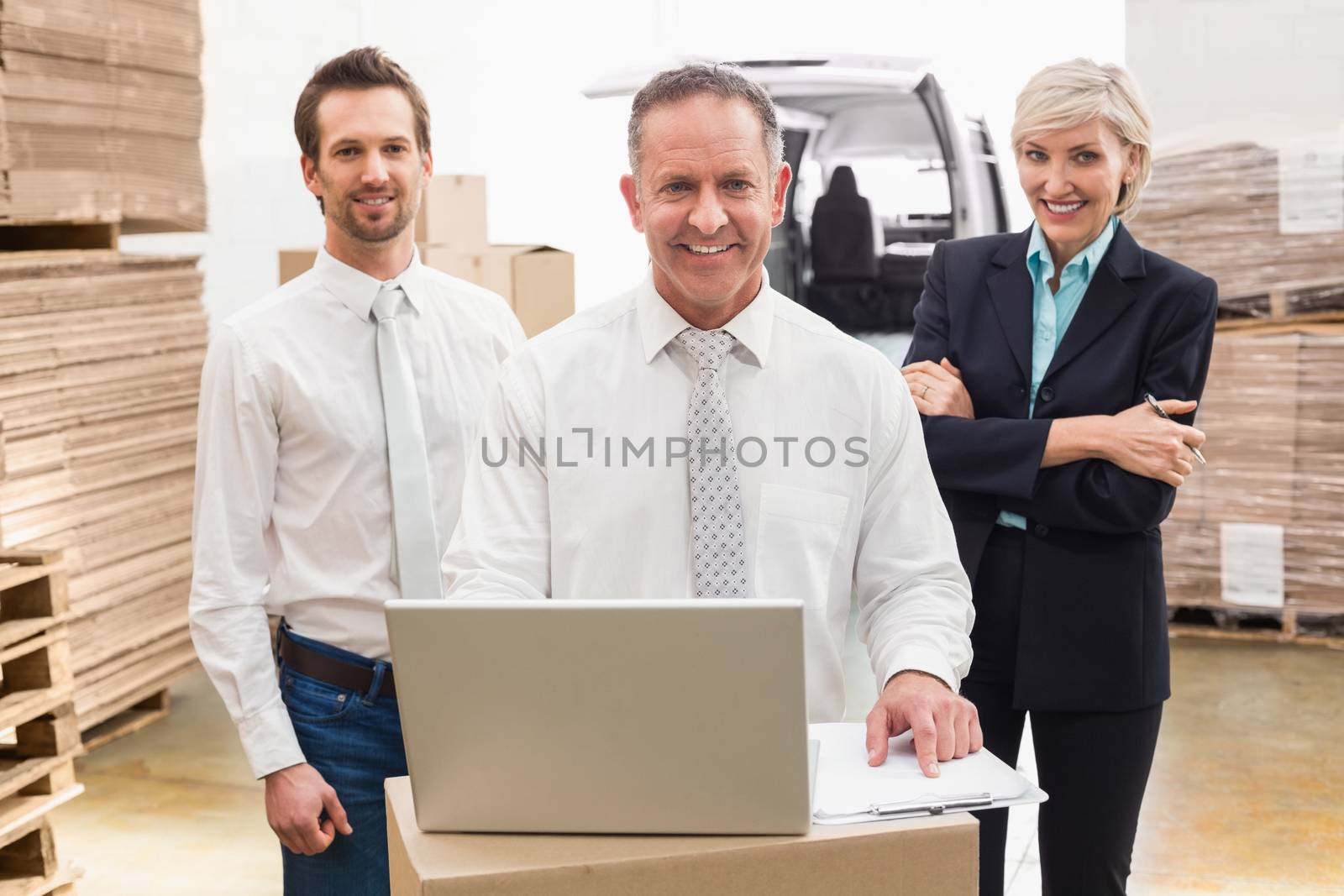 Warehouse team working together on laptop in a large warehouse