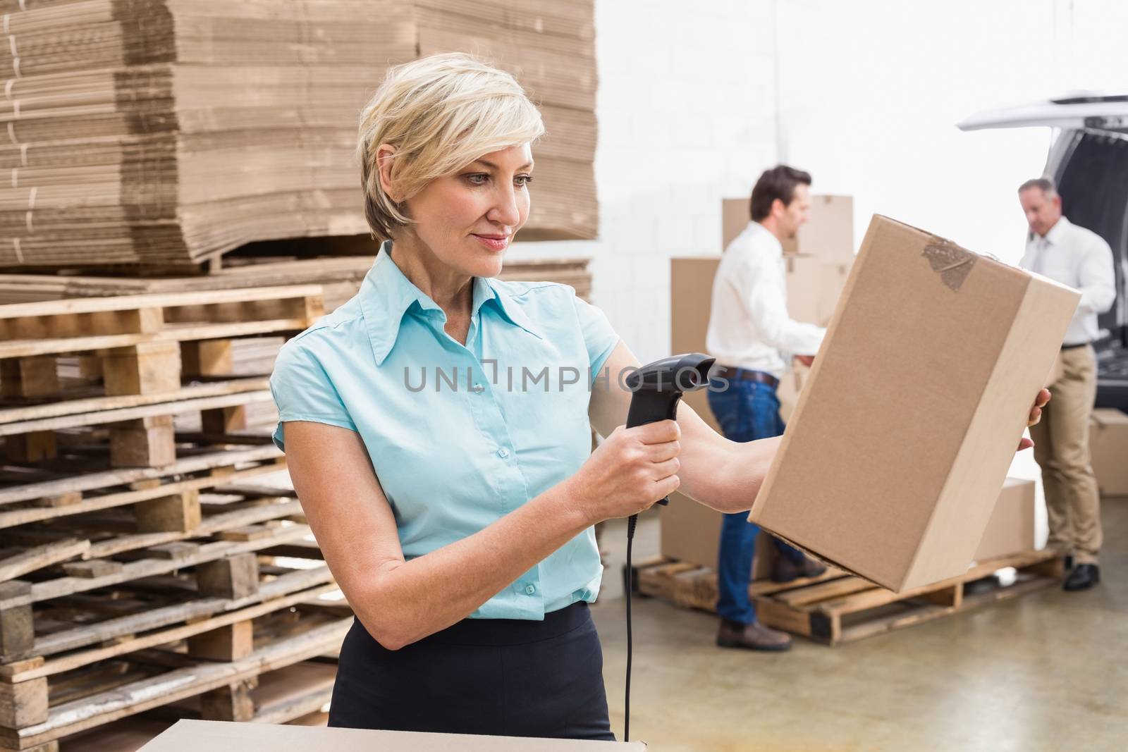 Smiling warehouse manager scanning package in warehouse