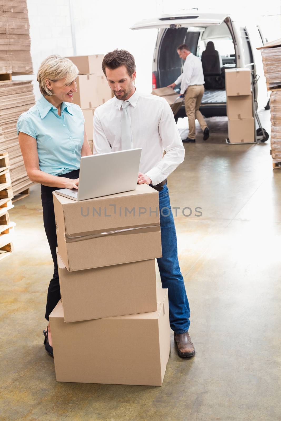 Colleague with laptop at warehouse by Wavebreakmedia