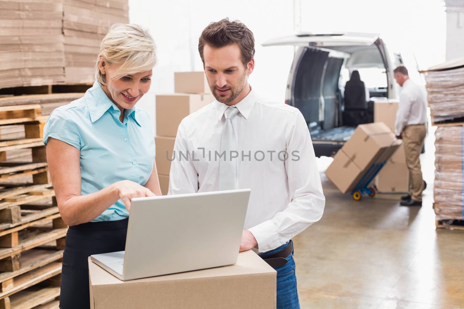 Warehouse manager and colleague using laptop