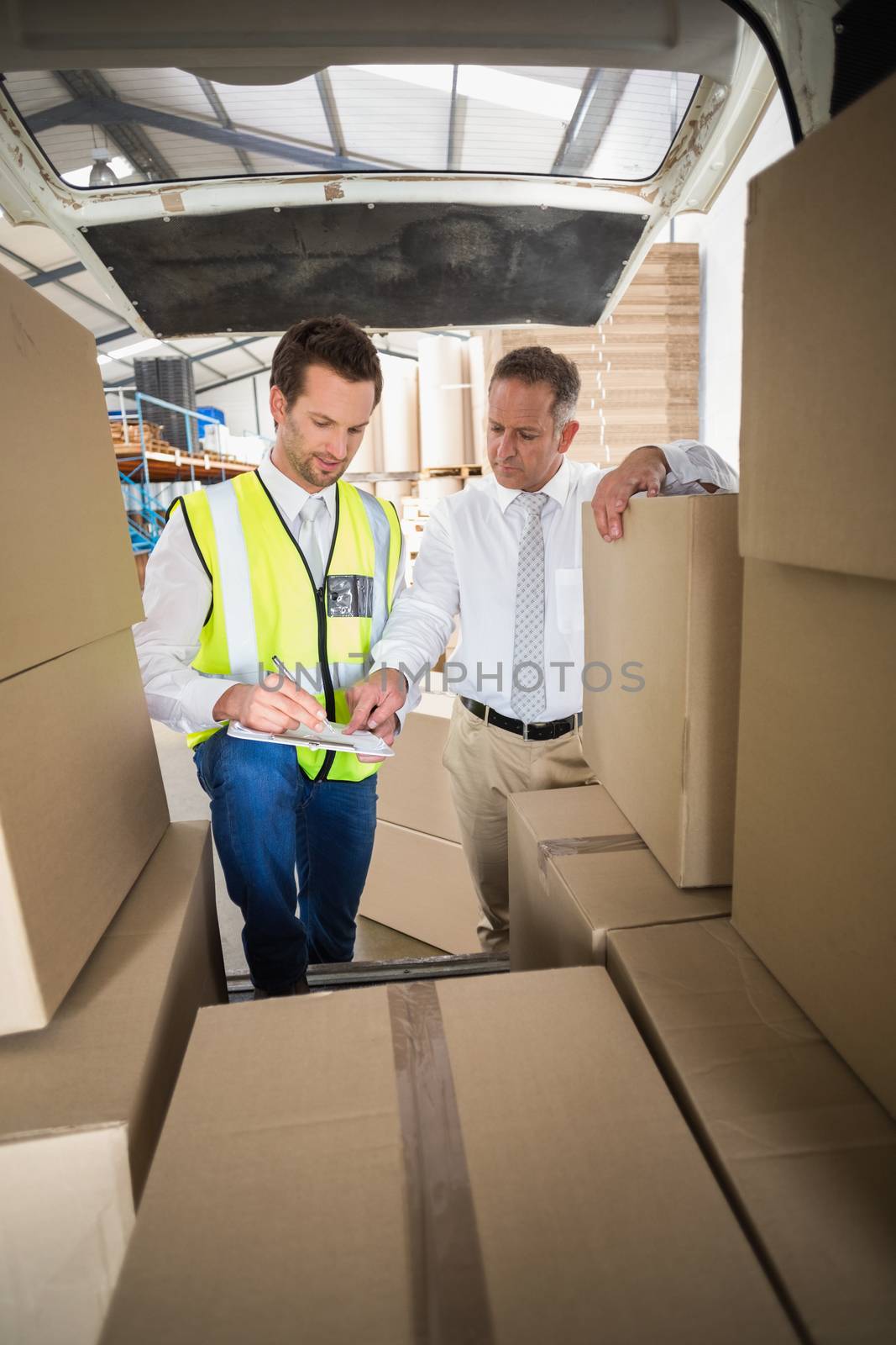 Delivery driver checking his list on clipboard in a large warehouse