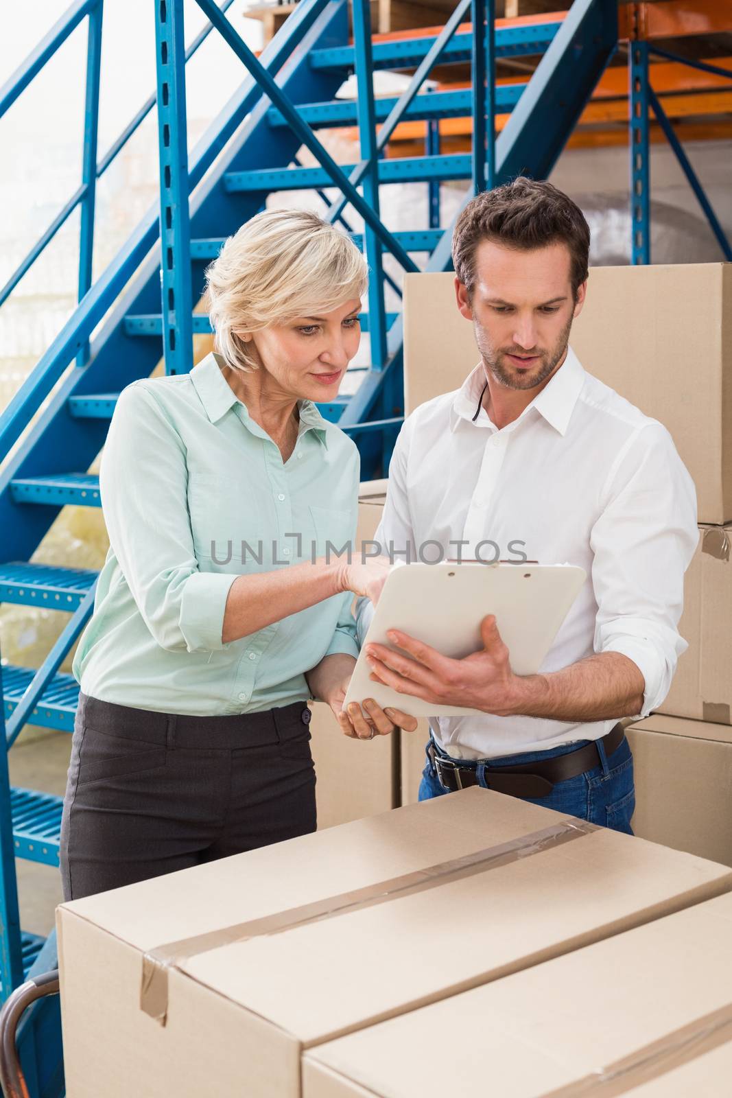 Focused warehouse managers with clipboard in a large warehouse